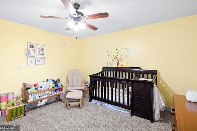 carpeted bedroom featuring ceiling fan and a crib