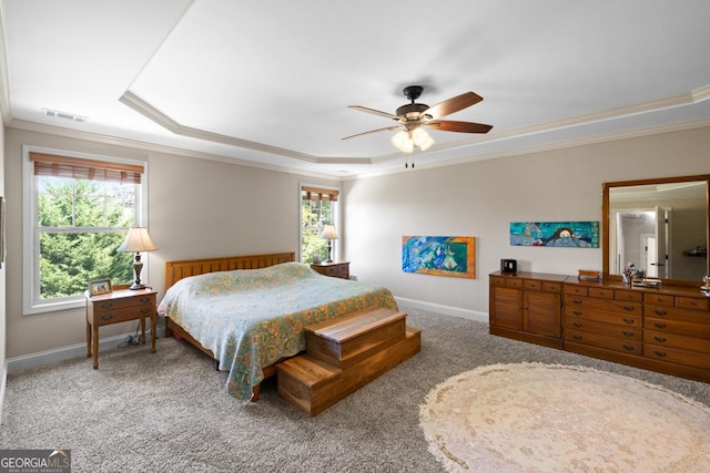 carpeted bedroom featuring ceiling fan, a raised ceiling, crown molding, and multiple windows