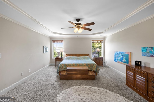 carpeted bedroom with ceiling fan, crown molding, and a tray ceiling