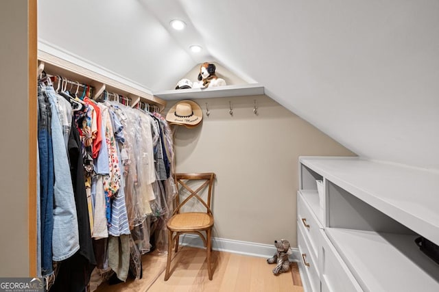 spacious closet with light hardwood / wood-style floors and vaulted ceiling