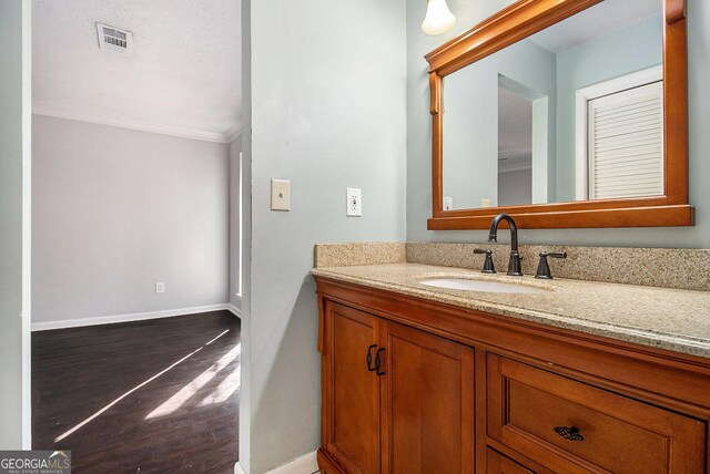 bathroom featuring crown molding, vanity, and wood-type flooring