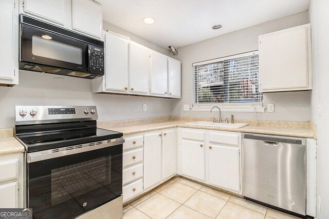 kitchen with light tile patterned flooring, appliances with stainless steel finishes, sink, and white cabinets