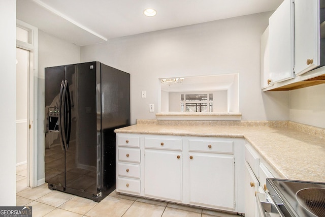 kitchen with light tile patterned floors, an inviting chandelier, black fridge, stove, and white cabinets