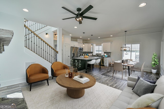 living room with ceiling fan with notable chandelier, light hardwood / wood-style floors, and sink