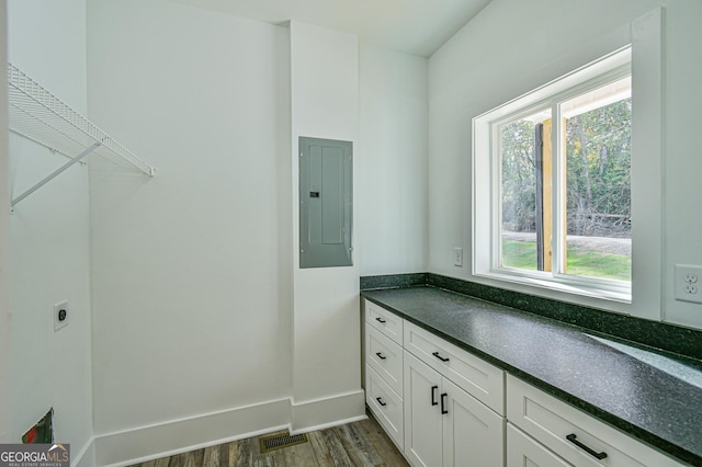 laundry area featuring electric dryer hookup, electric panel, cabinets, and dark hardwood / wood-style floors