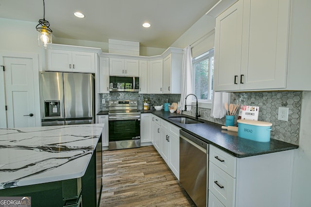 kitchen with white cabinets, decorative light fixtures, sink, and appliances with stainless steel finishes