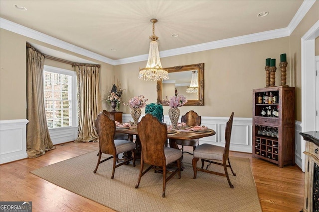 dining space featuring a chandelier, light wood-type flooring, and crown molding