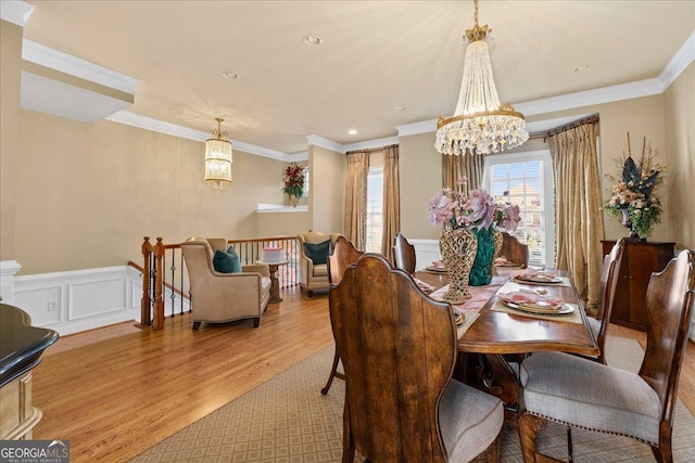 dining space featuring light wood-type flooring, ornamental molding, and a chandelier