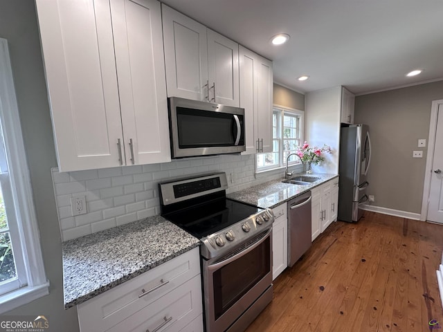 kitchen featuring appliances with stainless steel finishes, light stone counters, white cabinetry, and sink