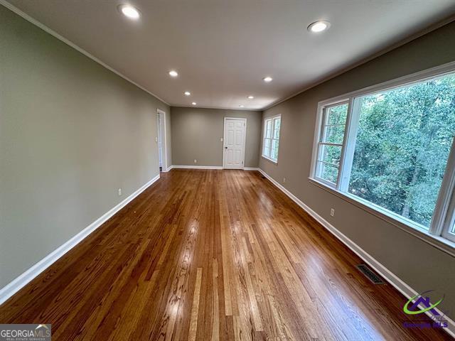 empty room with hardwood / wood-style flooring and ornamental molding