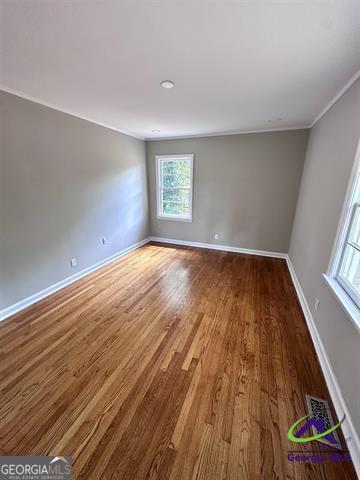 spare room with wood-type flooring and crown molding