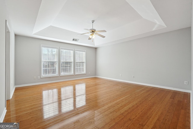 unfurnished room with ceiling fan, a raised ceiling, and light hardwood / wood-style flooring