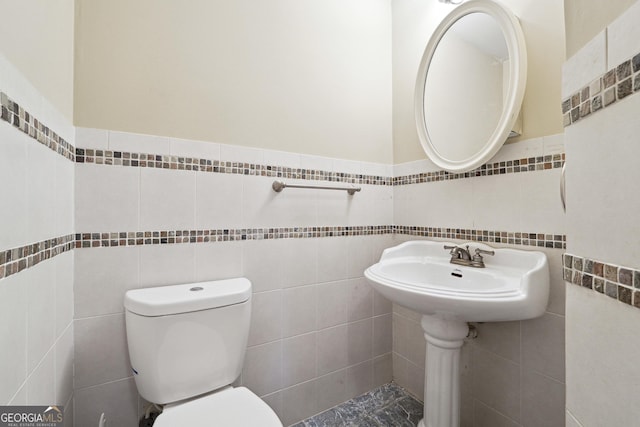 bathroom with sink, tile walls, and toilet