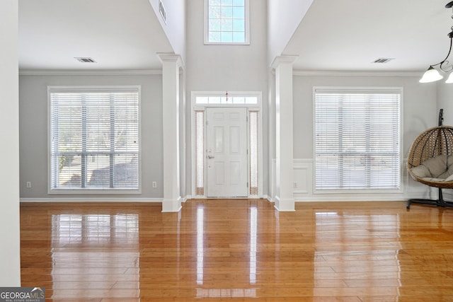 foyer entrance with a chandelier, hardwood / wood-style floors, decorative columns, and ornamental molding