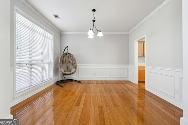 unfurnished dining area with a notable chandelier, ornamental molding, and light hardwood / wood-style flooring