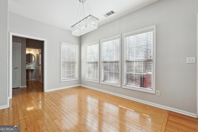 unfurnished dining area featuring light hardwood / wood-style flooring and a chandelier