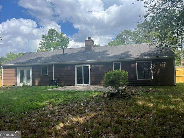 rear view of property featuring a lawn, central air condition unit, a patio, and french doors