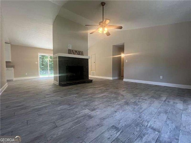 unfurnished living room with dark hardwood / wood-style flooring, vaulted ceiling, and ceiling fan