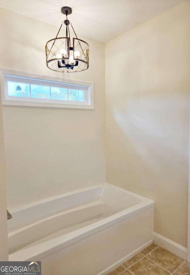 bathroom featuring tile patterned floors, a washtub, and an inviting chandelier