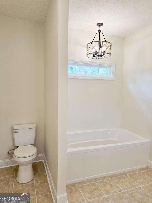 bathroom featuring a notable chandelier, toilet, a textured ceiling, and a tub