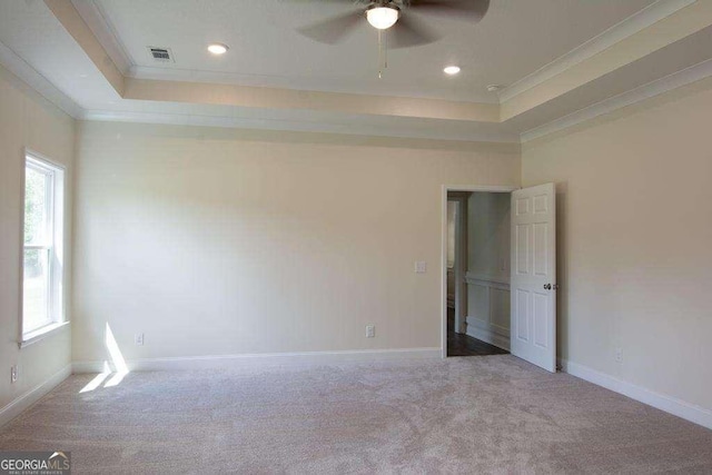 carpeted empty room featuring a tray ceiling, ceiling fan, and crown molding