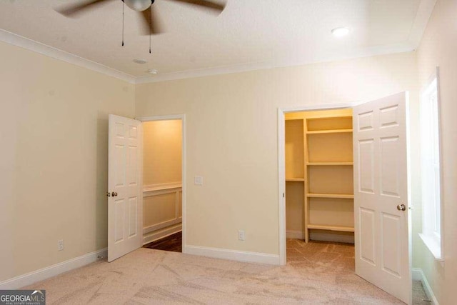 unfurnished bedroom with light carpet, a walk in closet, ceiling fan, and ornamental molding