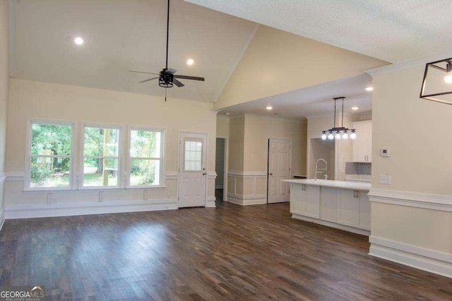 unfurnished living room featuring ceiling fan, dark wood-type flooring, and high vaulted ceiling