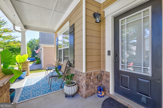 doorway to property featuring stone siding and covered porch