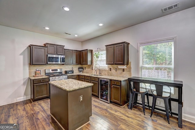 kitchen with beverage cooler, a sink, visible vents, appliances with stainless steel finishes, and a center island