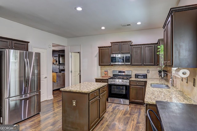 kitchen featuring a center island, dark wood-style flooring, stainless steel appliances, visible vents, and a sink