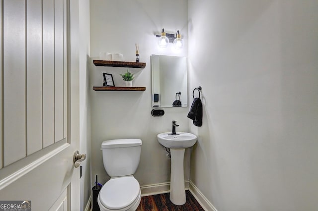 bathroom with toilet, baseboards, and wood finished floors