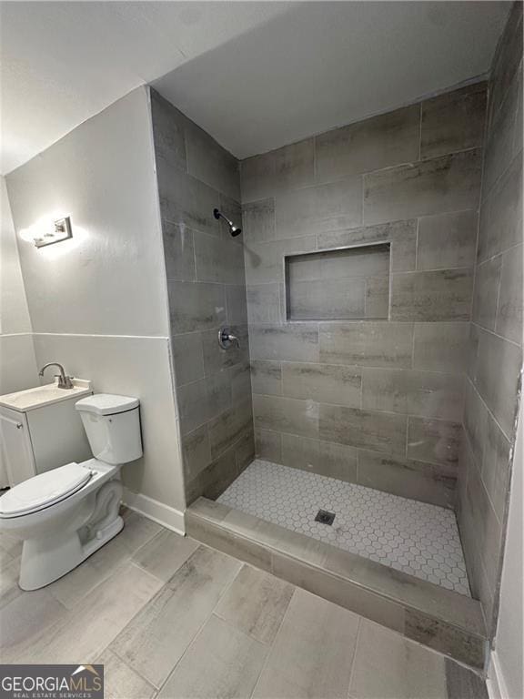 bathroom with a tile shower and toilet