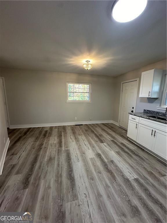 kitchen with white cabinets, light wood-type flooring, sink, and dark stone counters