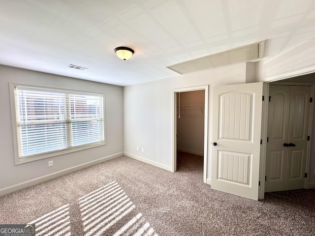 unfurnished bedroom featuring a closet, a spacious closet, and carpet floors