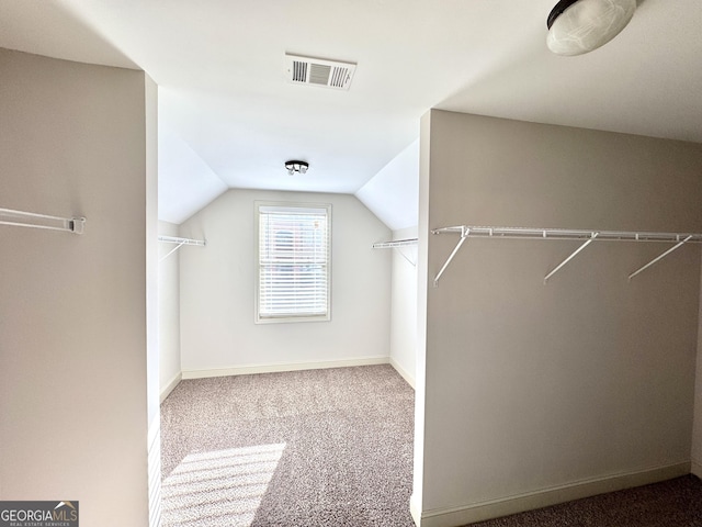 walk in closet with vaulted ceiling and carpet