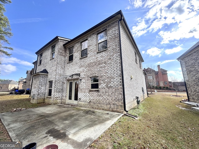 rear view of house featuring a lawn and a patio