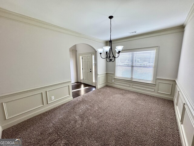 carpeted spare room with an inviting chandelier and ornamental molding