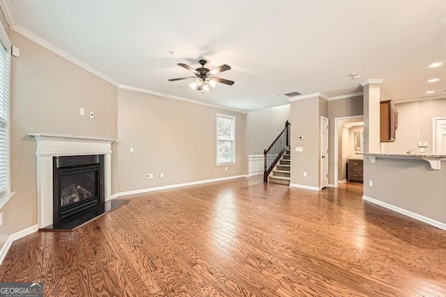 unfurnished living room featuring hardwood / wood-style floors, ceiling fan, and crown molding