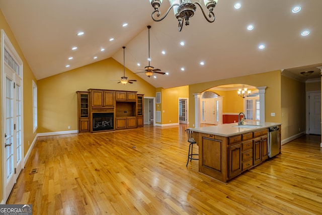 kitchen with sink, stainless steel dishwasher, a large island, a breakfast bar area, and decorative columns