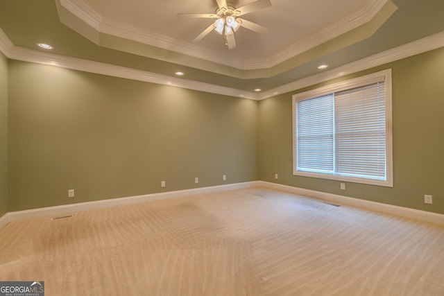 spare room featuring a tray ceiling, ceiling fan, crown molding, and light colored carpet