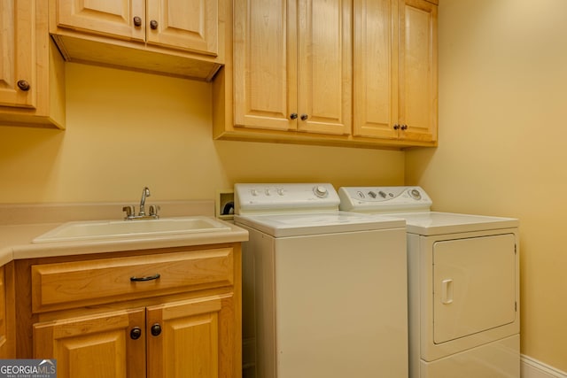 clothes washing area featuring cabinets, washer and dryer, and sink