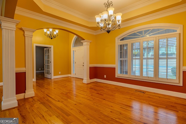 unfurnished room with decorative columns, an inviting chandelier, plenty of natural light, and ornamental molding