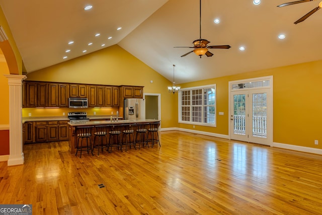 kitchen featuring decorative columns, a breakfast bar, stainless steel appliances, sink, and a large island