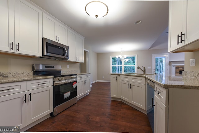 kitchen with white cabinets, light stone countertops, appliances with stainless steel finishes, a notable chandelier, and kitchen peninsula