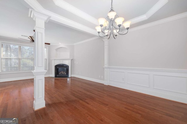 unfurnished living room with dark wood-type flooring, an inviting chandelier, a raised ceiling, crown molding, and ornate columns