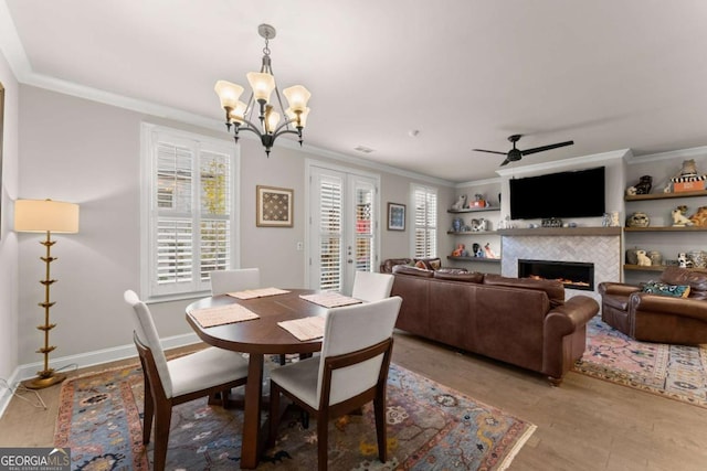 dining area featuring a fireplace, light wood-type flooring, a wealth of natural light, and crown molding