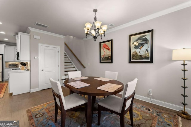 dining space with an inviting chandelier, dark hardwood / wood-style floors, and ornamental molding