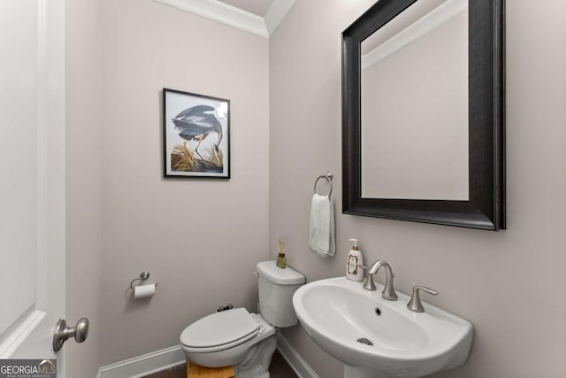 bathroom with toilet, sink, and ornamental molding