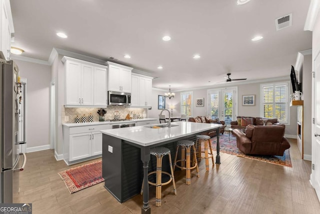 kitchen featuring white cabinets, sink, an island with sink, and stainless steel appliances