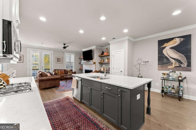 kitchen featuring ceiling fan, a kitchen island with sink, sink, gray cabinets, and a breakfast bar area